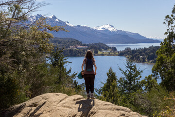 Mujer con mochila observa un paisaje de lagos y montañas