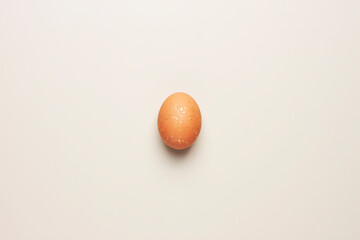 Easter beige and golden egg on pastel background. Flat lay, copy space