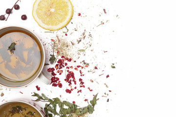 Herbal tea, top view with copy spce. Dry herbs, lemon slices and tea cups on white. Herbs in bulk,...