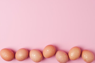 Easter beige eggs on a pink background. Flat lay, copy space.