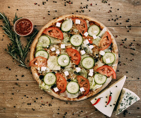 Vegetable pizza with mozzarella, fresh tomatoes and cucumber