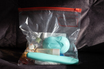 travel kit: shampoo, soap, toothbrush in a transparent zip bag on dark background