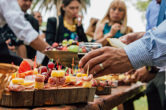 Manos tomando alimentos de una mesa de banquete