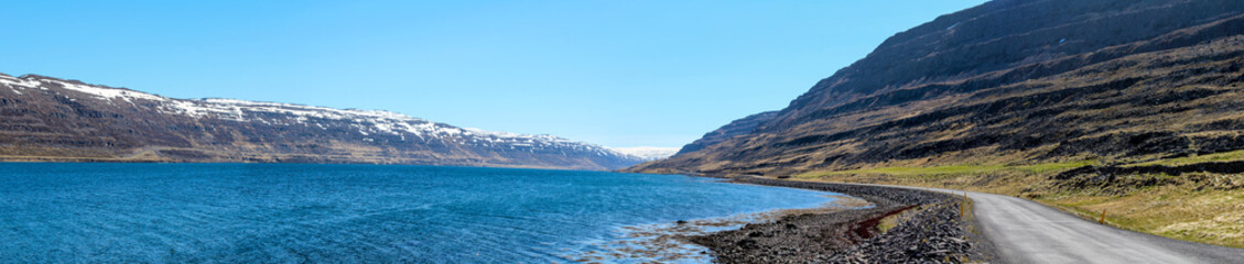 Fototapeta premium Panoramic view of a gravelled road at a fjord, Westfjords