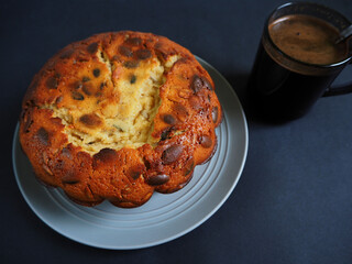 round pumpkin pie made of corn and rice flour on a gray plate next to a glass coffee mug on a dark background side view . gluten-free baked goods made at home