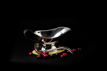 a stainless steel creamer and coffees spoon isolated on black