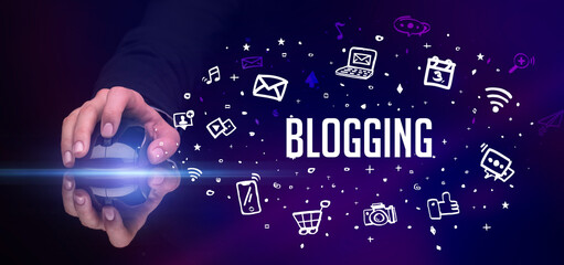 hand holding wireless peripheral with BLOGGING inscription, social media concept
