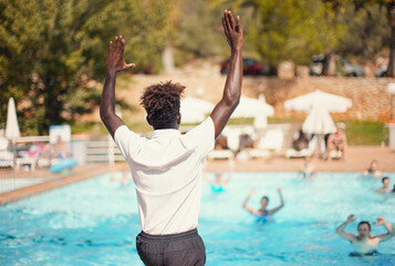 Black athletic hotel resort animator exercising in front of pool, view form behind blurred people...