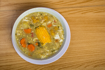 tazón con vista superior de sopa condimentada con pollo triturado, huevo y maíz en el centro, concepto de vida saludable en casa
