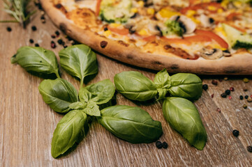Fragrant basil leaves decorate hot pizza