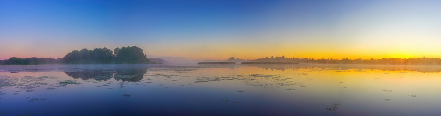 Fototapeta na wymiar Panorama with beautiful foggy sunrise over forest lake