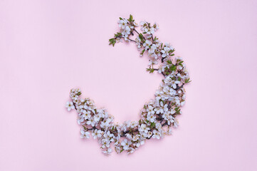 Round frame wreath made of spring flowers on pink background. Top view. The concept of spring and March 8