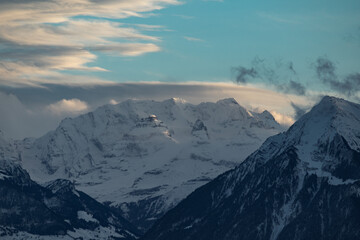 swiss mountains during sunset with fog and clouds and snowy mountains in the alps
