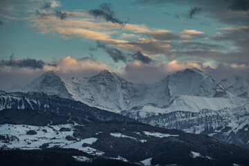 Fototapeta na wymiar swiss mountains during sunset with fog and clouds and snowy mountains in the alps