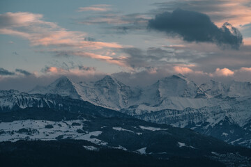 swiss mountains during sunset with fog and clouds and snowy mountains in the alps