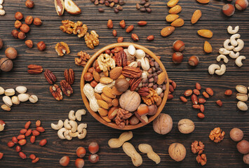 Assortment of nuts in bowls. Cashews, hazelnuts, walnuts, pistachios, pecans, pine nuts, peanuts, macadamia, almonds, brazil nuts. Food mix on wooden background, top view, copy space