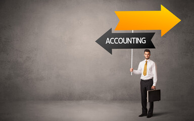 Young business person in casual holding road sign with ACCOUNTING inscription, business direction concept