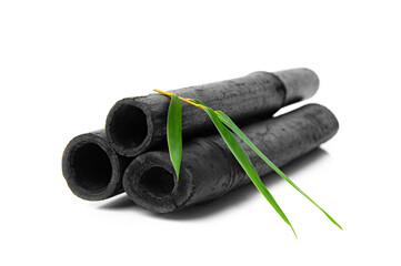 Bamboo activated charcoal sticks and green leaf isolated on white background.