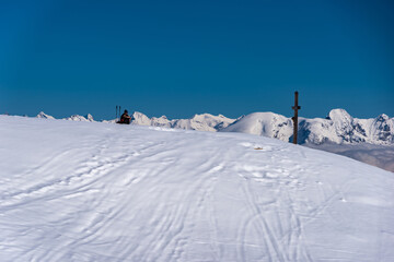 Fototapeta na wymiar Schneebedeckter Gipfel mit Gipfelkreuz vor blauem Himmel