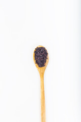 Black wild rice in a wooden spoon on white background.