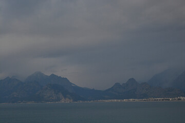 sea, grey clouds and mountains with foggy weather, settlements