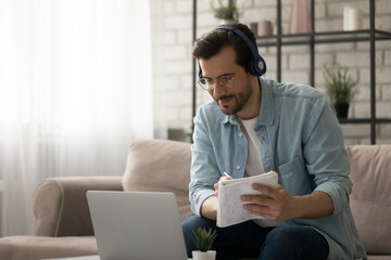 Confident male student in wireless headset sit on sofa watch education video online from university...