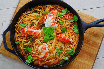 A dish of tomato linguine pasta with lobster tails and fresh basil