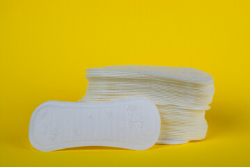 A stack of sanitary pads on a yellow background close-up.
