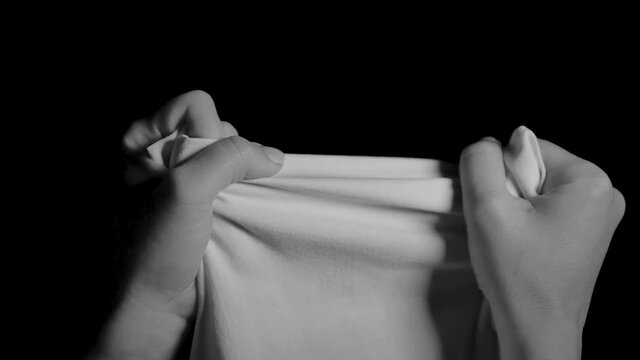 Hands try to tear a white cloth.
Dramatic black and white scene of hands pulling hard. A blanket hard to tear. Hands trembling with effort.