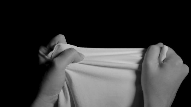 Hands try to tear a white cloth.
Dramatic black and white scene of hands pulling hard. A blanket hard to tear. Hands trembling with effort.