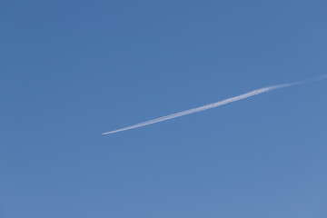 Airliner flies high in the sky. There is a line behind the plane.