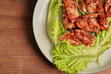 Caramelized chicken close-up top view. Asian recipe for caramelized chicken fillet slices on a plate in lettuce leaves with space to copy text