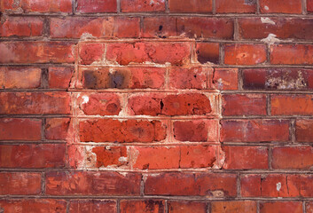 Obraz premium old brick textured and scratched wall with repaired area - close up, red old building patterned background