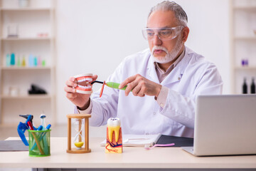 Old male dentist working in the clinic