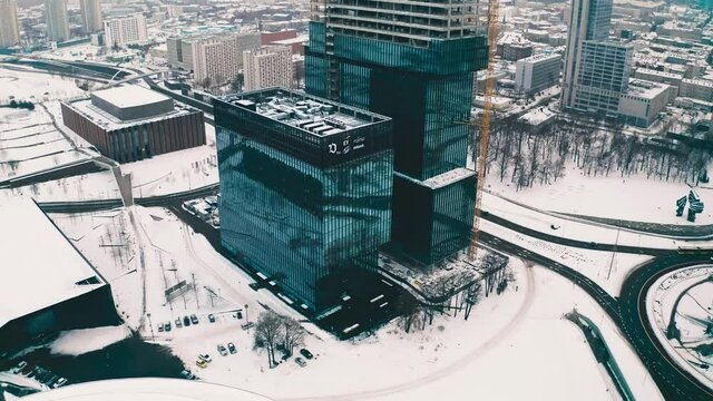 Modern glass office skyscrapers under construction .KTW in Katowice, Poland in snowy winter aerial drone view 4k