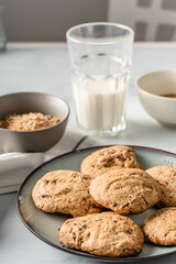 Close up front view on crunchy oatmeal chip cookies fresh baked biscuits with chocolate and cocoa in a plate on the table and ingredients beside homemade food concept