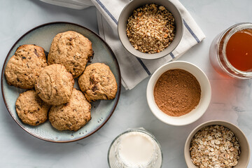 Close up top view on crunchy oatmeal chip cookies fresh baked biscuits with chocolate and cocoa in a plate on the table and ingredients beside homemade food concept