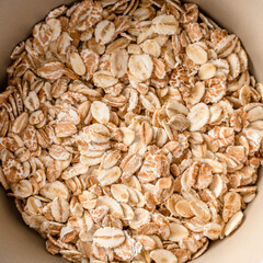 Close up top view on oat rye and wheat flakes in a bowl - vegan or vegetarian organic food concept