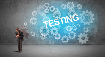 Fototapeta premium Businessman defending with umbrella from TESTING inscription, technology concept