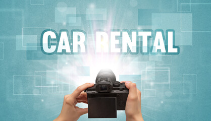 Close-up of a hand holding digital camera with CAR RENTAL inscription, traveling concept