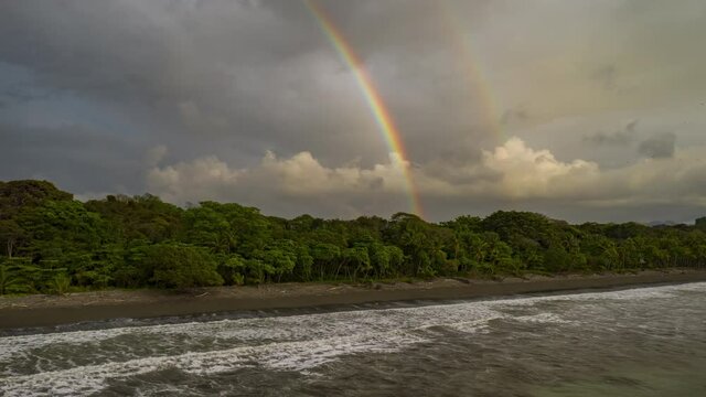 Aerial time lapse hyperlapse over a tropical beach with rainbow over the forest Costa Rica