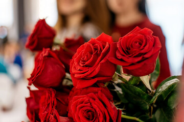 Bouquet of red roses with girls in the background