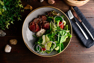 Grilled steak with green lettuce, cucumber and fresh rosemary. Home made tasty food. Concept for a tasty and healthy meal. fresh salad with grilled beef