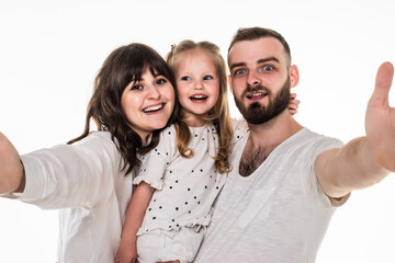 Full length portrait of a young family with a child standing together and taking a selfie isolated over white background