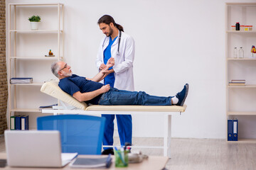 Old male patient visiting young male doctor chiropractor