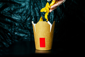 French fries flying in a cardboard box on a dark background