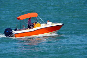 Small orange motor boat with white trim on Biscayne Bay off of Miami Beach,Florida.