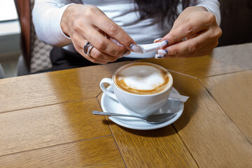 Obraz na płótnie Canvas A customer in a cafe pours sugar into a cup of coffee.