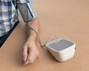an elderly man checking hypertension with a home blond pressure monitor
