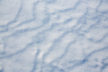 Beautiful winter background with snowy ground. Natural snow texture. Wind sculpted patterns on snow surface.
